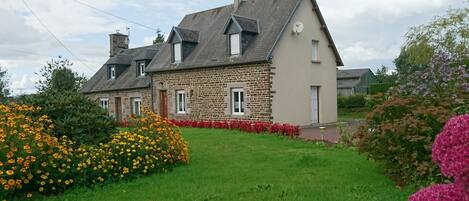 en premier plan le jardin fleuri puis la maison mitoyenne avec les propriétaire