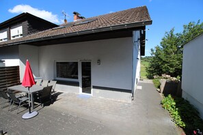 Terrasse mit großem Tisch und Holzkohlegrill