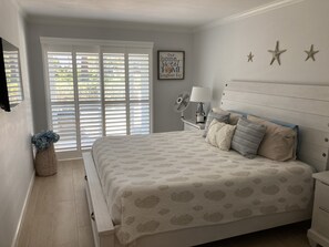 Bedroom with updated King sized bed and mounted TV. 