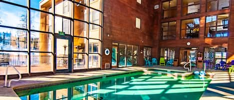 Indoor heated pool with view of BBQ deck