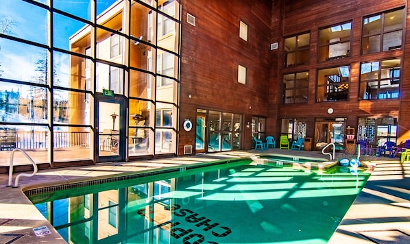 Indoor heated pool with view of BBQ deck