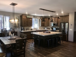 LARGE OPEN KITCHEN WITH TONS OF SEATING AROUND LARGE ISLAND AND TABLE 