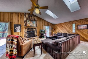 Living room provides wood burning fireplace, sliding glass doors to upper deck and vaulted ceilings with skylights.