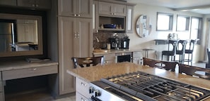 Gas stove top, desk area to left, beverage cooler and coffee area, bar seating