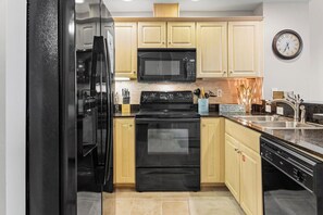 Kitchen - Managing meals will be a breeze in this fully stocked kitchen featuring black appliances, and all items needed for meal prepping.