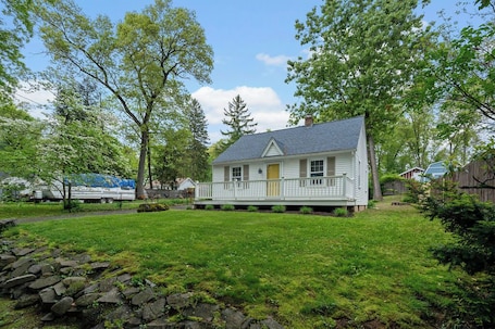 Bright cottage with a porch, tucked in a quiet, grassy yard.