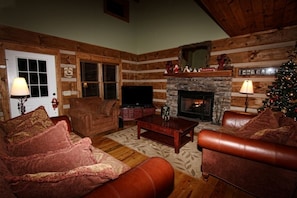 Cozy living area surrounding hand-stacked stoned fireplace and 65" HD television