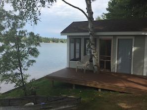 Screened in boat house with loveseat, lounges, and gas fireplace inside