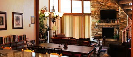 Living/Dining Room showing custom Sofas, TV, Loft Stairs & Soaring Ceilings