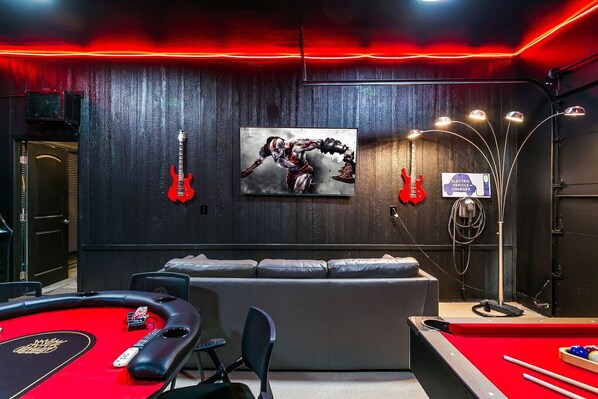 The newly remodeled Hard Roq themed game room/party area has a golf simulator, 7' pool table, 8 seater poker table, skee-ball, retro video game, 65"TV, sofa sleeper, refrigerator