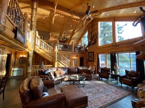 The living room below, a massive wooden bar above, and lake views for miles