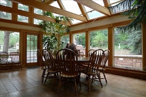 Dining Room located in a greenhouse has a  table that extends to seat up to 16.