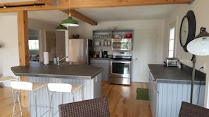 Kitchen area with stainless steel appliances and kitchen island and bar.