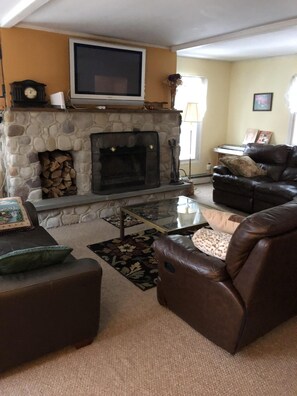 Living room with wood burning fireplace and large leather sectional