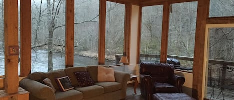 Great room surrounded by windows overlooking the river