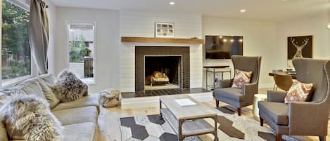 Main living room with fireplace, two chairs and a couch