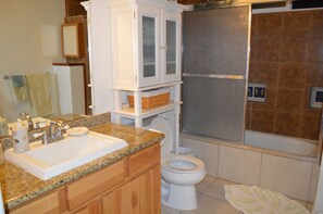 The bathroom is a tub/shower combo with a seating area. 