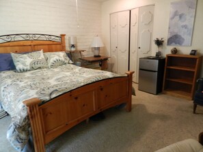 bed, refrigerator, computer desk with chair and 2 lamps and walk-in closet