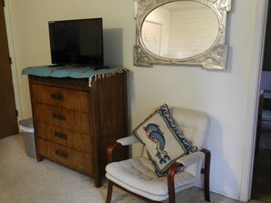 Dresser with TV beside mirror and chair