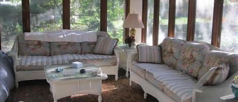 Cozy sunroom with wicker funiture and side panels covering screen as needed