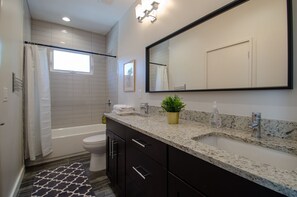 Large shared bathroom with double vanity sinks and lots of light. 