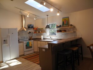 Clean and spacious kitchen has vaulted ceiling, skylight, TV, and walk in pantry