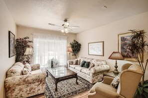 Sunlight filters from the bay window into living room's conversational seating.
