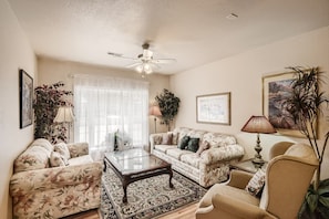 Sunlight filters from the bay window into living room's conversational seating.