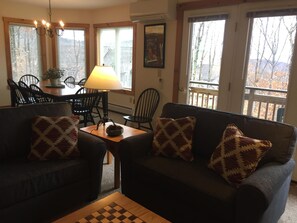 Living and dining area look out over the deck, trail and mountains.