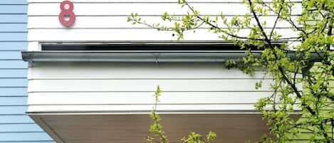 Glass doors with the blinds drawn.  Front deck shelter.  Green back yard. 