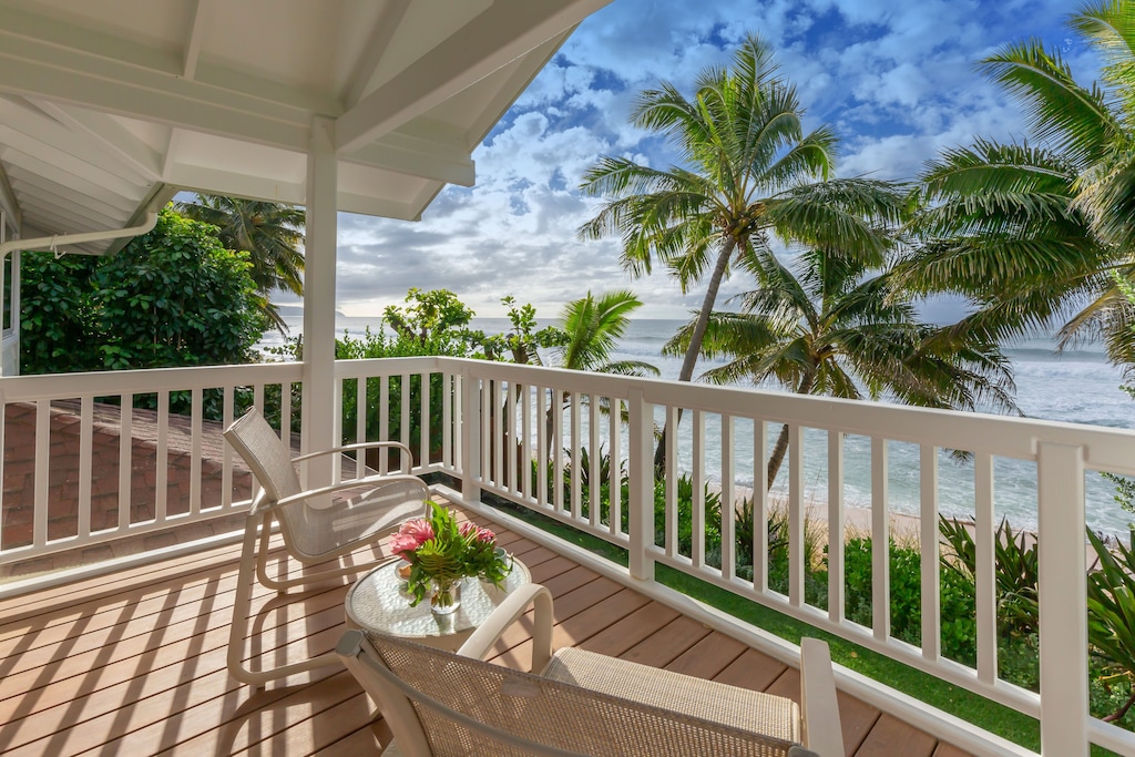 Find out the best villas on Oahu recommended by top Hawaii blog Hawaii Travel with Kids Image of a lanai overlooking the ocean and palm trees.