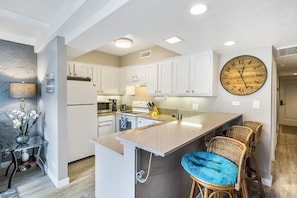 Fully equipped kitchen with bar-style seating and fridge.