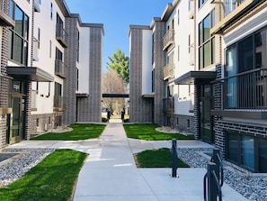 View from parking lot. Small courtyard. Bike Racks 