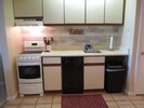 Kitchen with stove, dishwasher, microwave, cutlery, dishes, and utensils