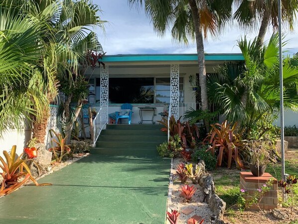 Front entrance to 3-bedroom home showing tropical foliage