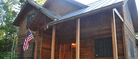 Front of the home in the summer. The home is completely surrounded by forest