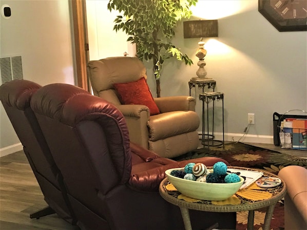 cozy living room with a double recliner loveseat and two single recliners.