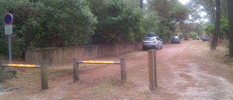 vue du parking, la maison et l'entrée se trouvent au niveau de la  voiture grise