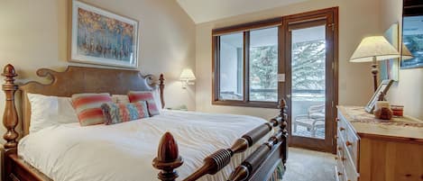 Warm and inviting bedroom with large windows framing scenic outdoor views.