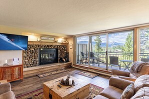 Living area offering cozy furnishings, mountain views, and a wood-burning fireplace.