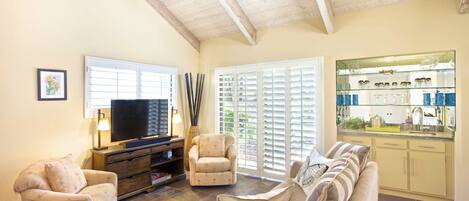 Living room with granite wet bar, pull-out queen sofa, fan, and new television.