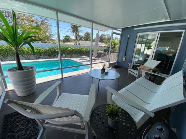 The lanai looks upon the private heated pool situated in a tropical landscape