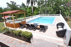 Poolside spa with swimming pool also pool furniture with BBQ pit to the left