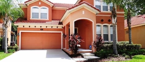 Front view of the home with large 3-4 car driveway, complete with Palm Trees.