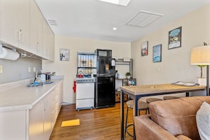 Kitchen counter with sink, kitchen with an electric stove, fridge, microwave