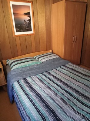 Double bed bedroom with a night table and a wardrobe.

