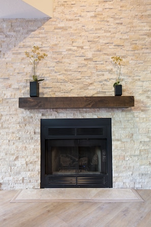 Gorgeous gas burning fireplace with marble hearth and stone surround
