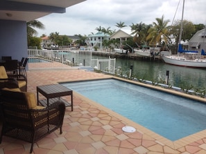 Pool with patio sofa and chairs view onto dock and canal