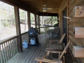 Covered side porch with gas grill, dining table  and chairs and wood recliners.