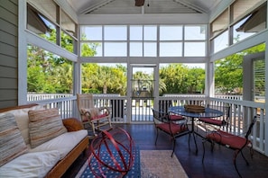 Screened porch overlooks pool and yard. TV, Table, rockers, couch. ceiling fan
